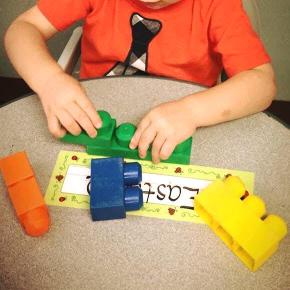 Child playing with colorful building blocks on a table