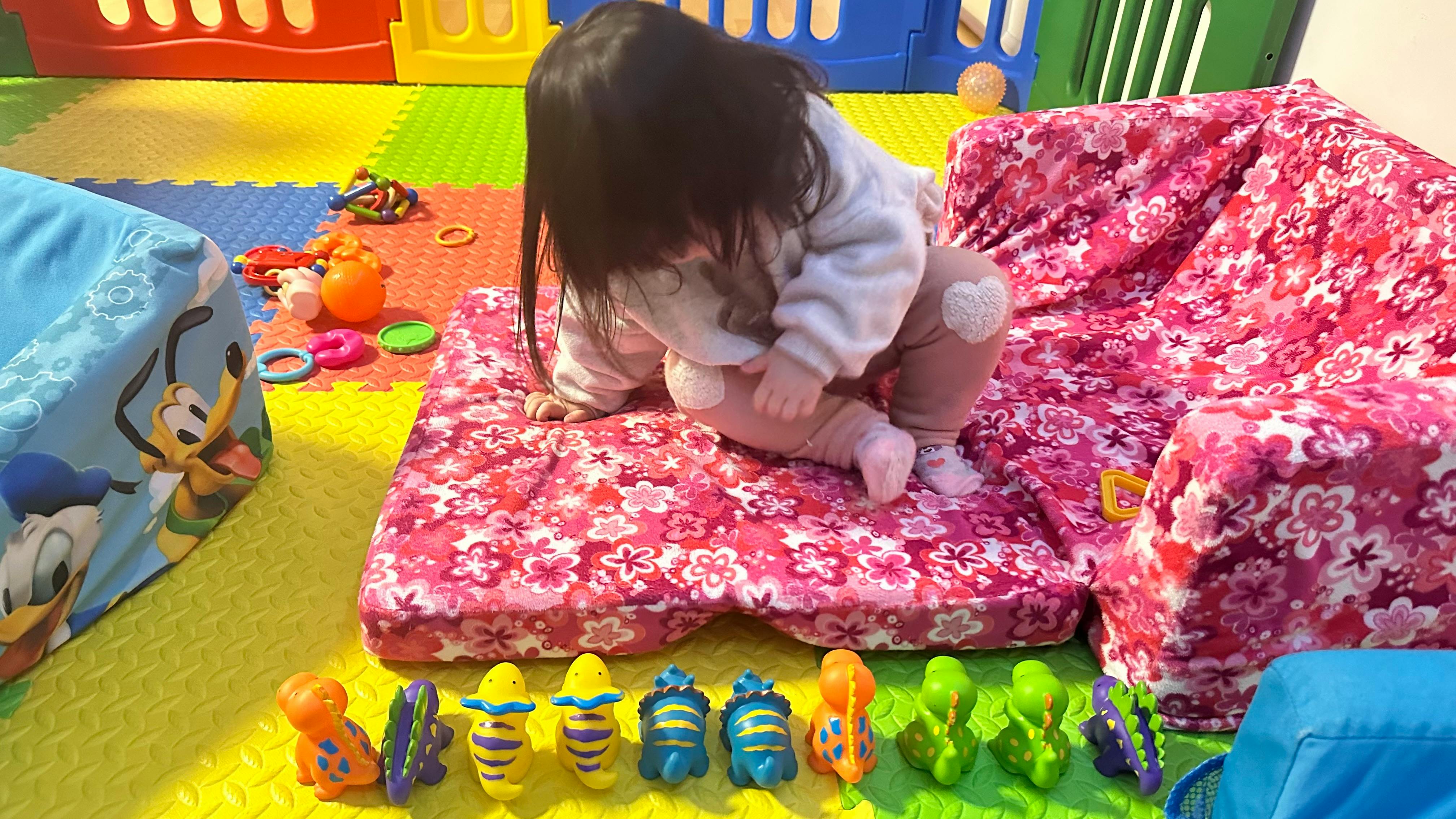 Child kneeling on a pink cushion