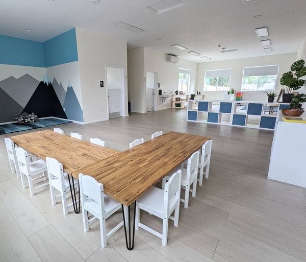 Empty classroom with a long wooden table and white chairs