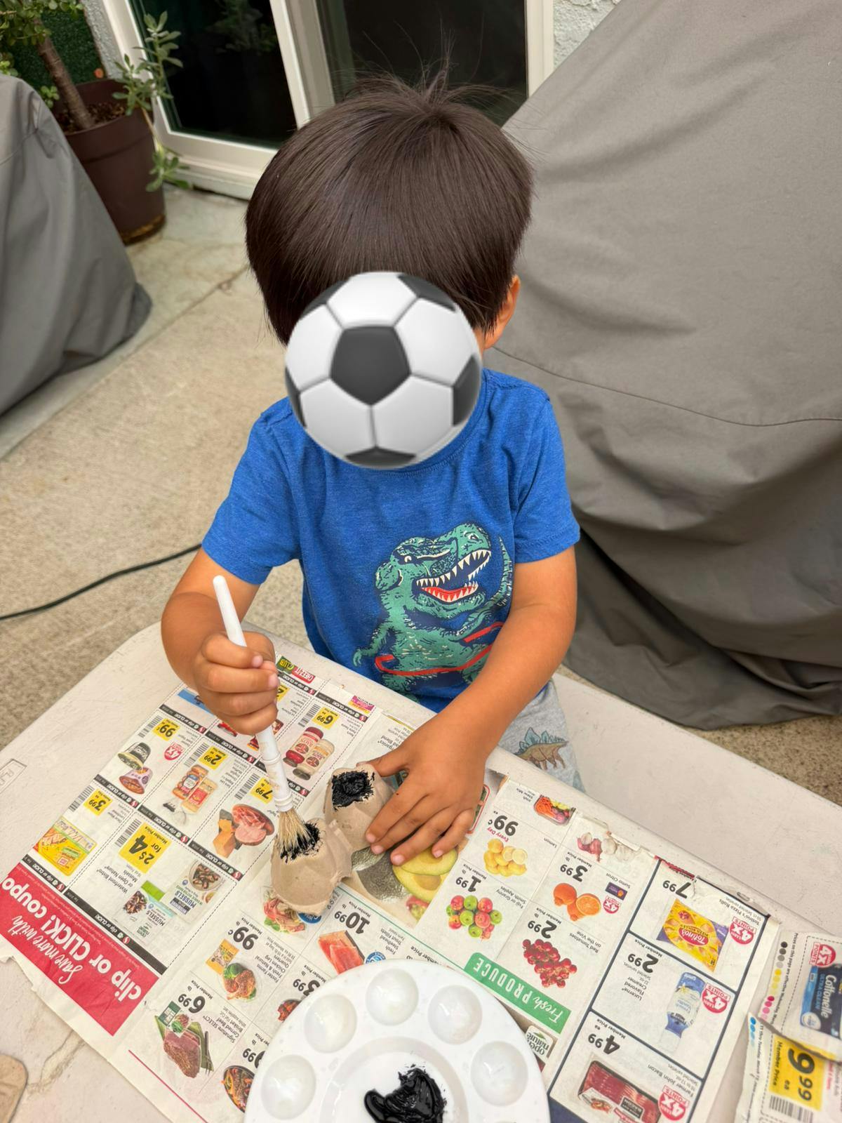 Child painting on an egg carton at a table covered with newspaper