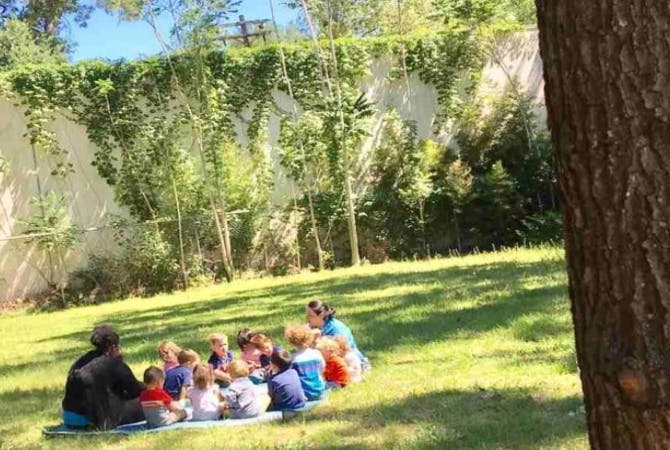 People and children sitting on a blanket on grass outdoors
