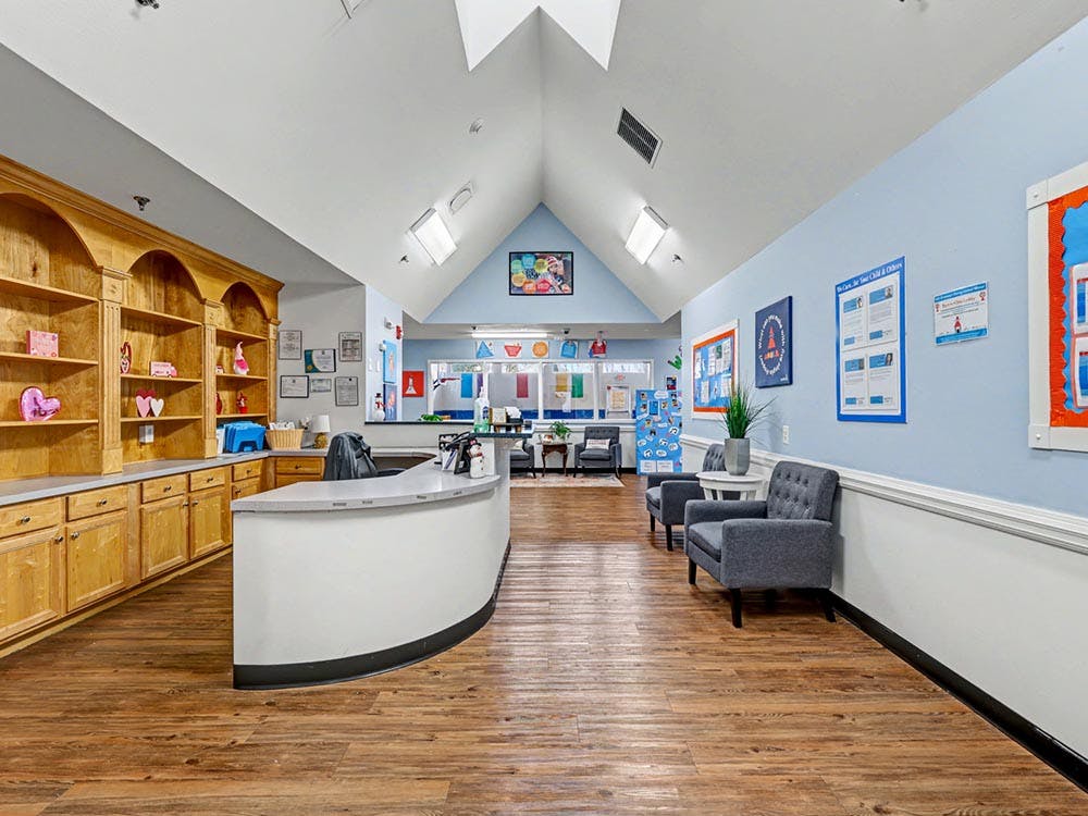 Reception area with a curved desk, wooden shelving, and seating
