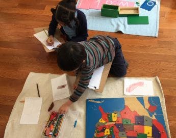 Two children on the floor with learning materials