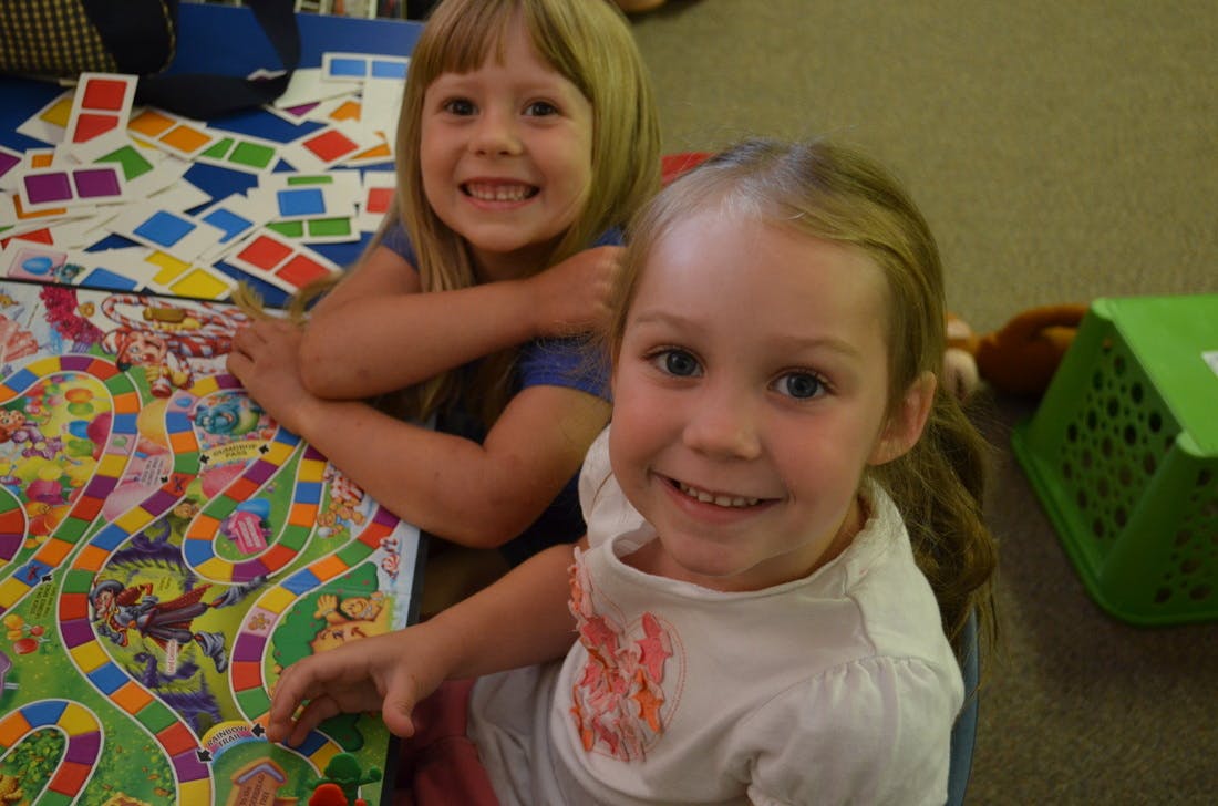 Two children playing a board game with colorful cards