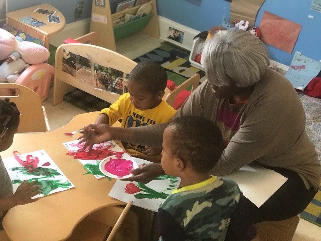 Adult and two children finger painting at a table