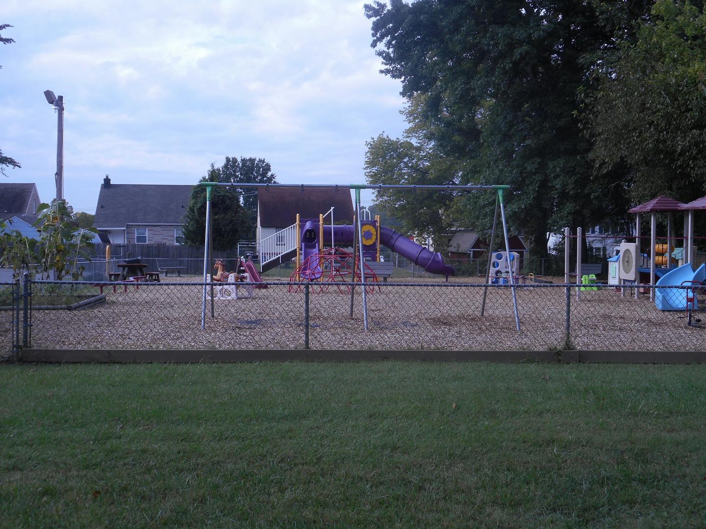 Empty playground with swings and slides behind a chain link fence