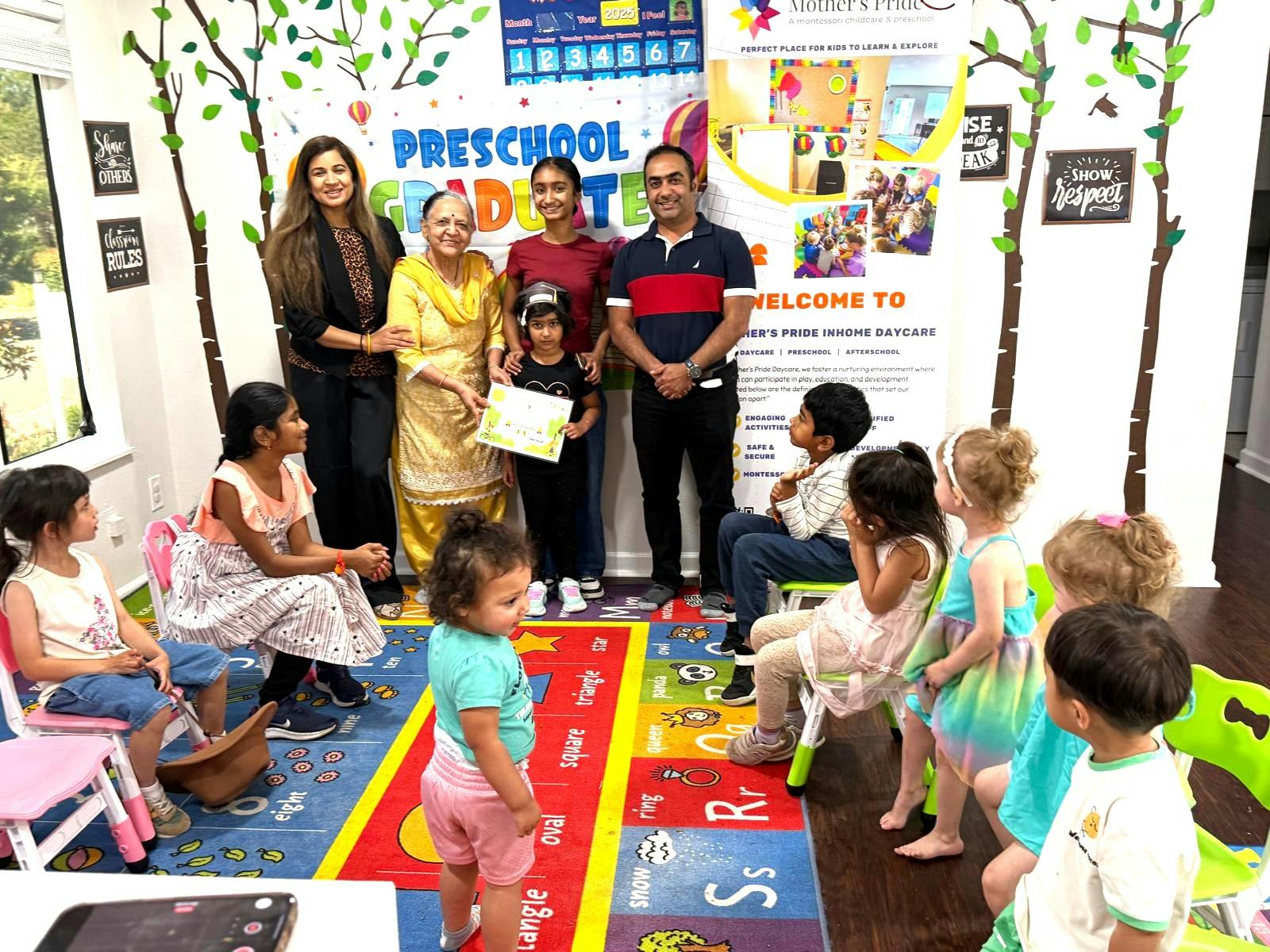 Adults and children gathered in a room with a "Preschool Graduate" banner