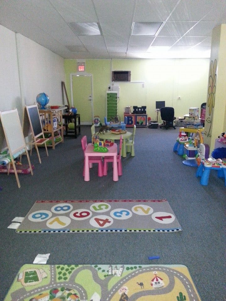 Classroom with small tables and chairs, easels, and play rugs