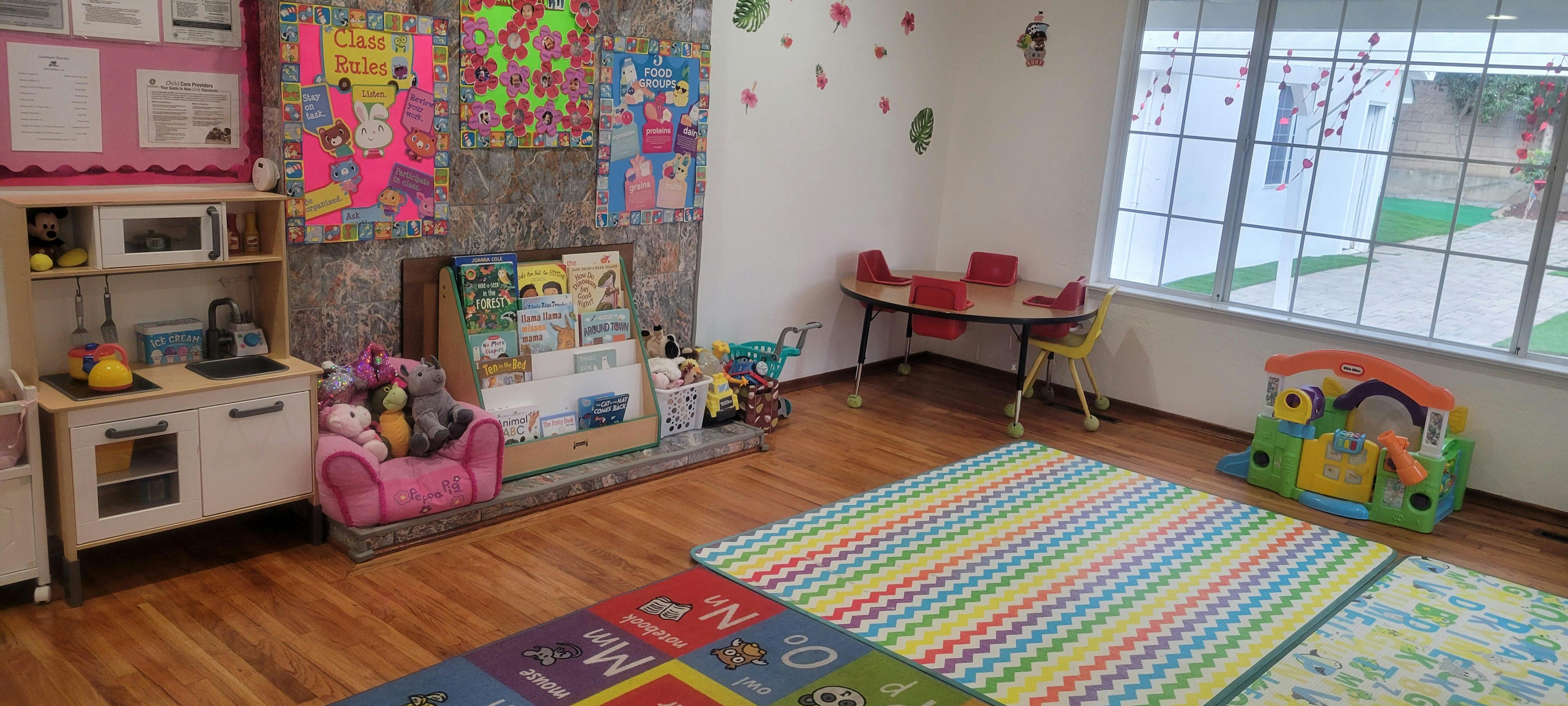 Playroom with toy kitchen, small table and chairs, and colorful rugs