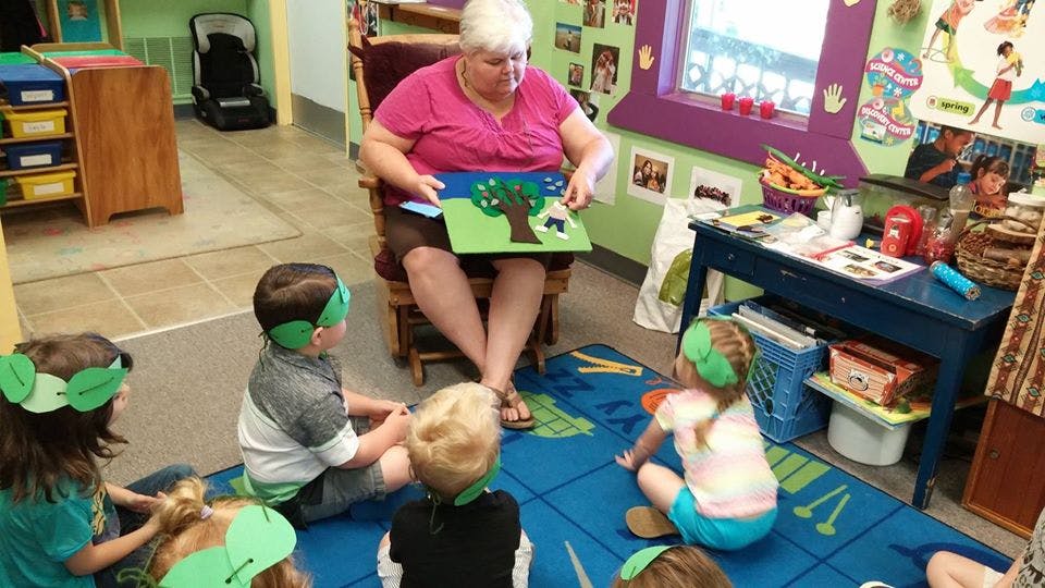Person reading a book to children in a classroom