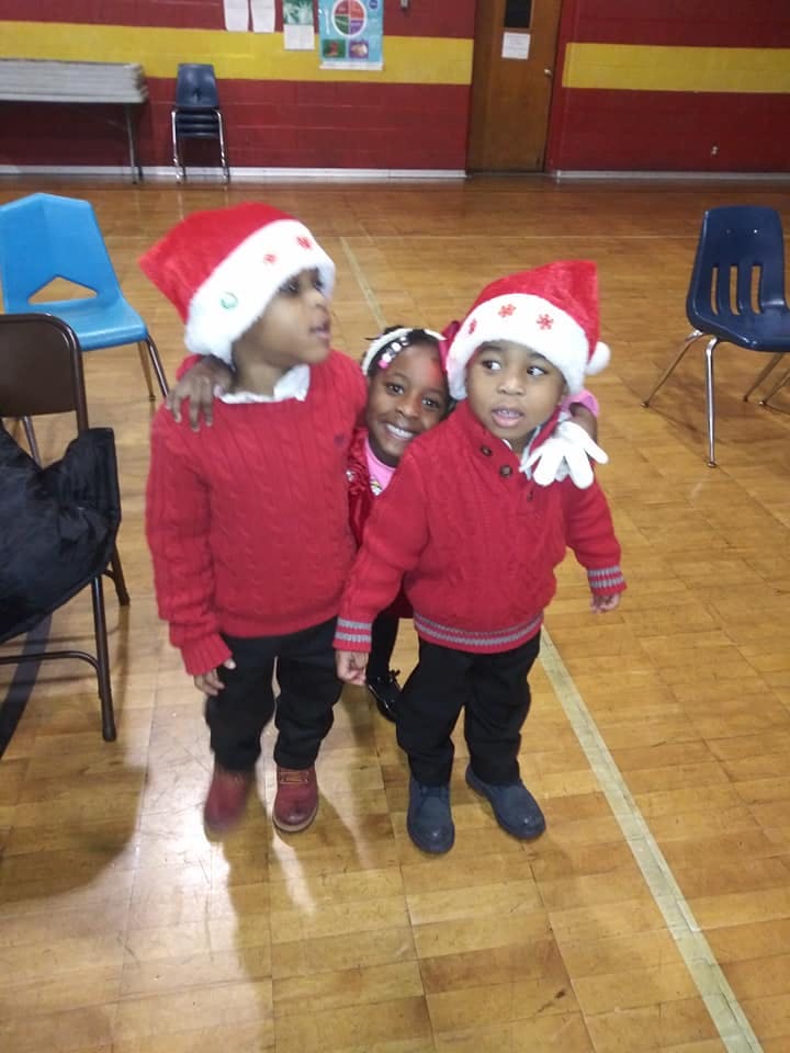 Three children wearing red sweaters and Santa hats