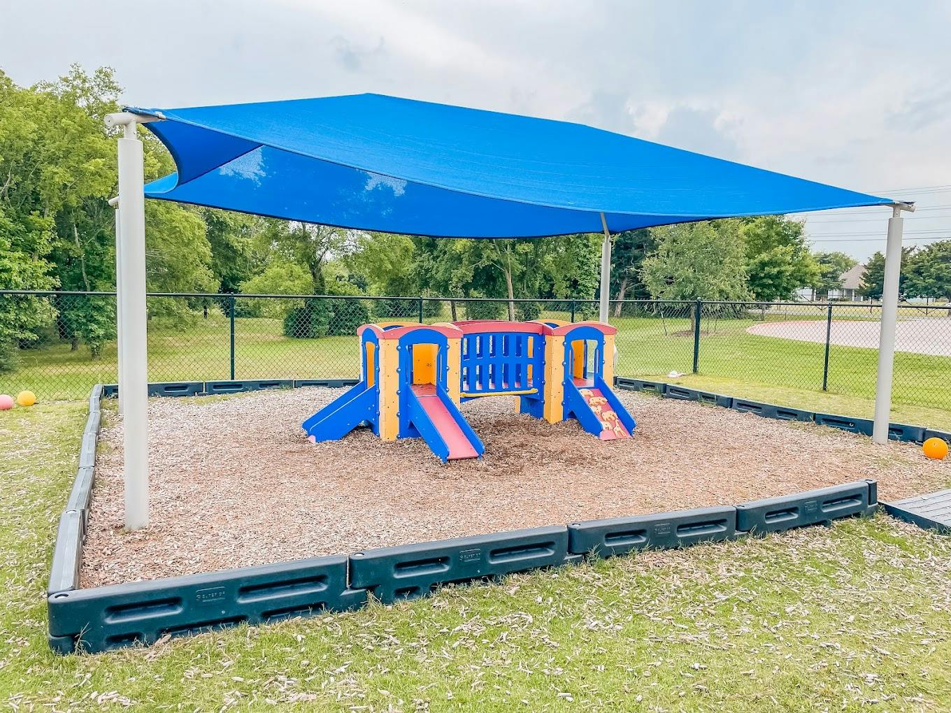 Small toddler playground structure under a blue shade canopy