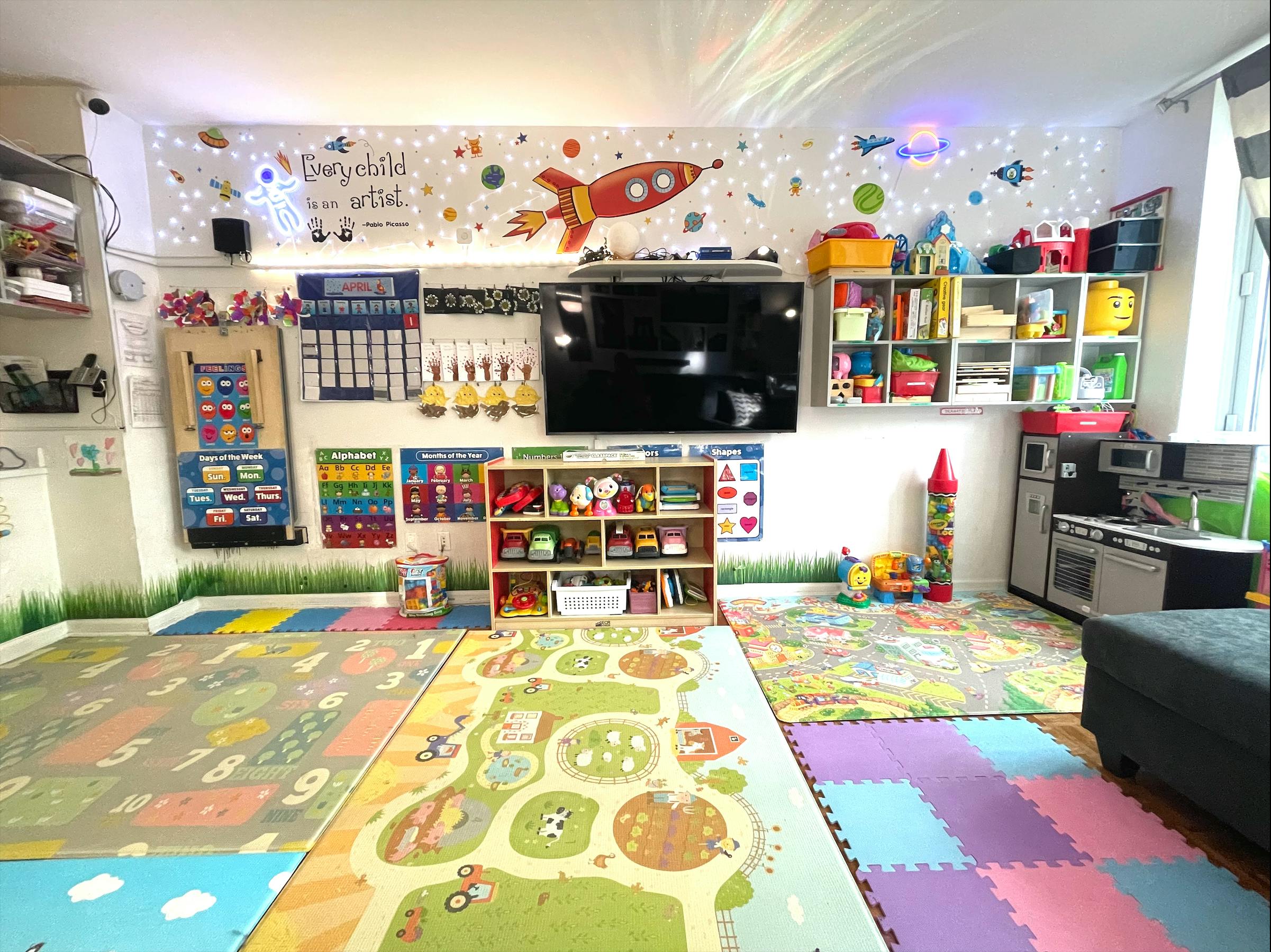 Playroom with space-themed wall decor, colorful floor mats, and toy shelves