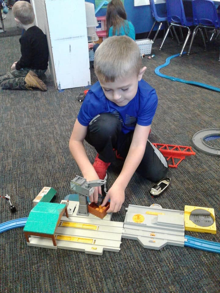 Child playing with a toy train set on the floor