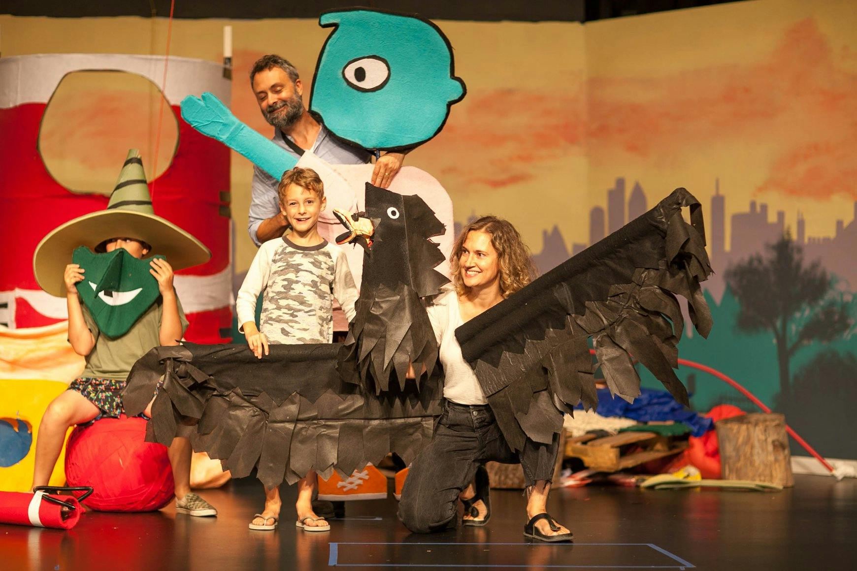 People and children on stage with large bird puppets and props