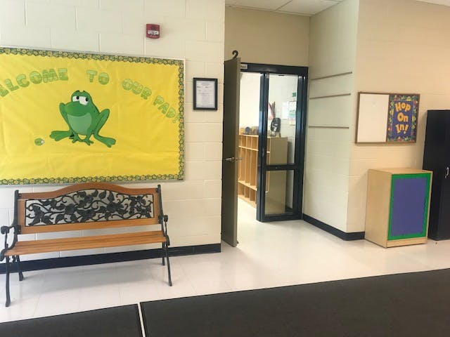 Hallway with a bench, bulletin board, and open doorway