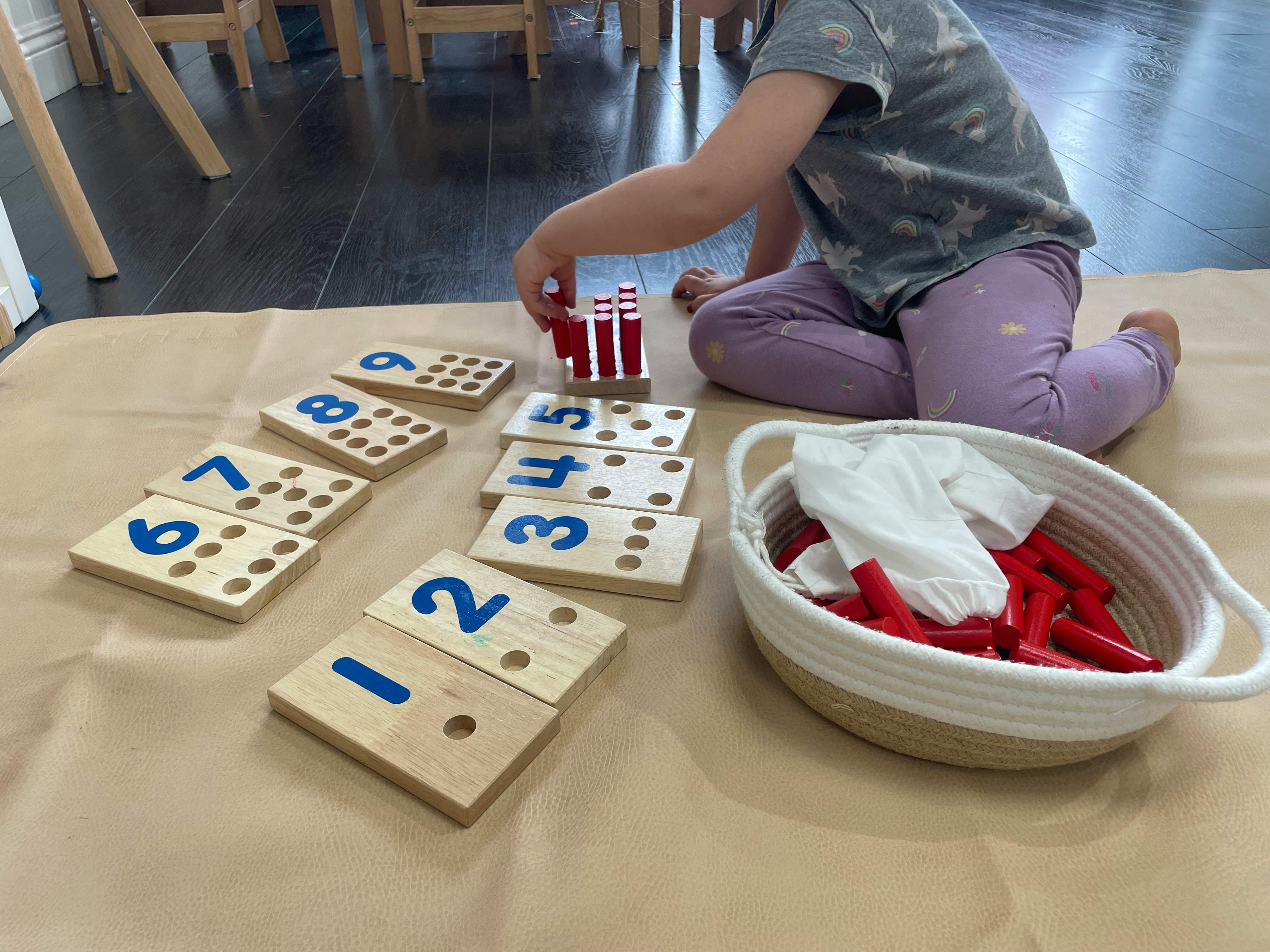 Child playing with wooden number blocks and red counting sticks
