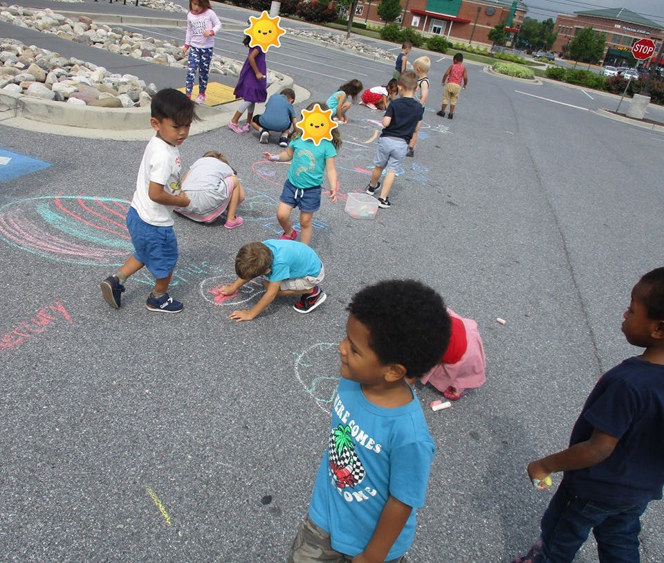 Children drawing with chalk on pavement