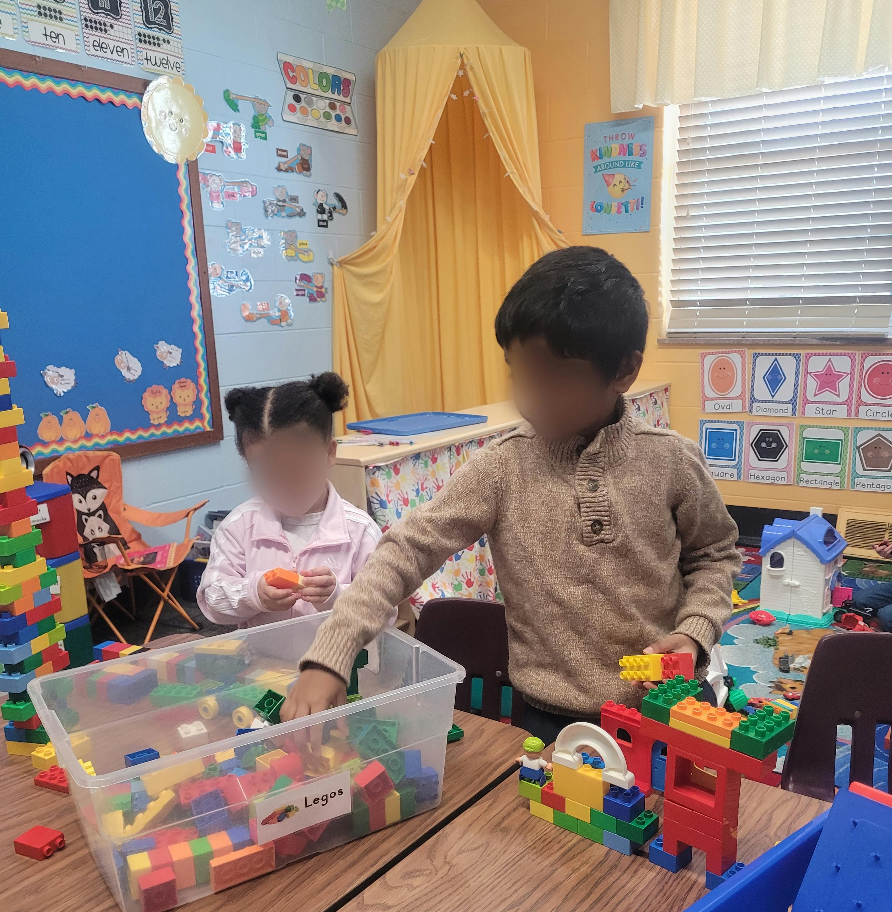 Two children playing with building blocks in a classroom