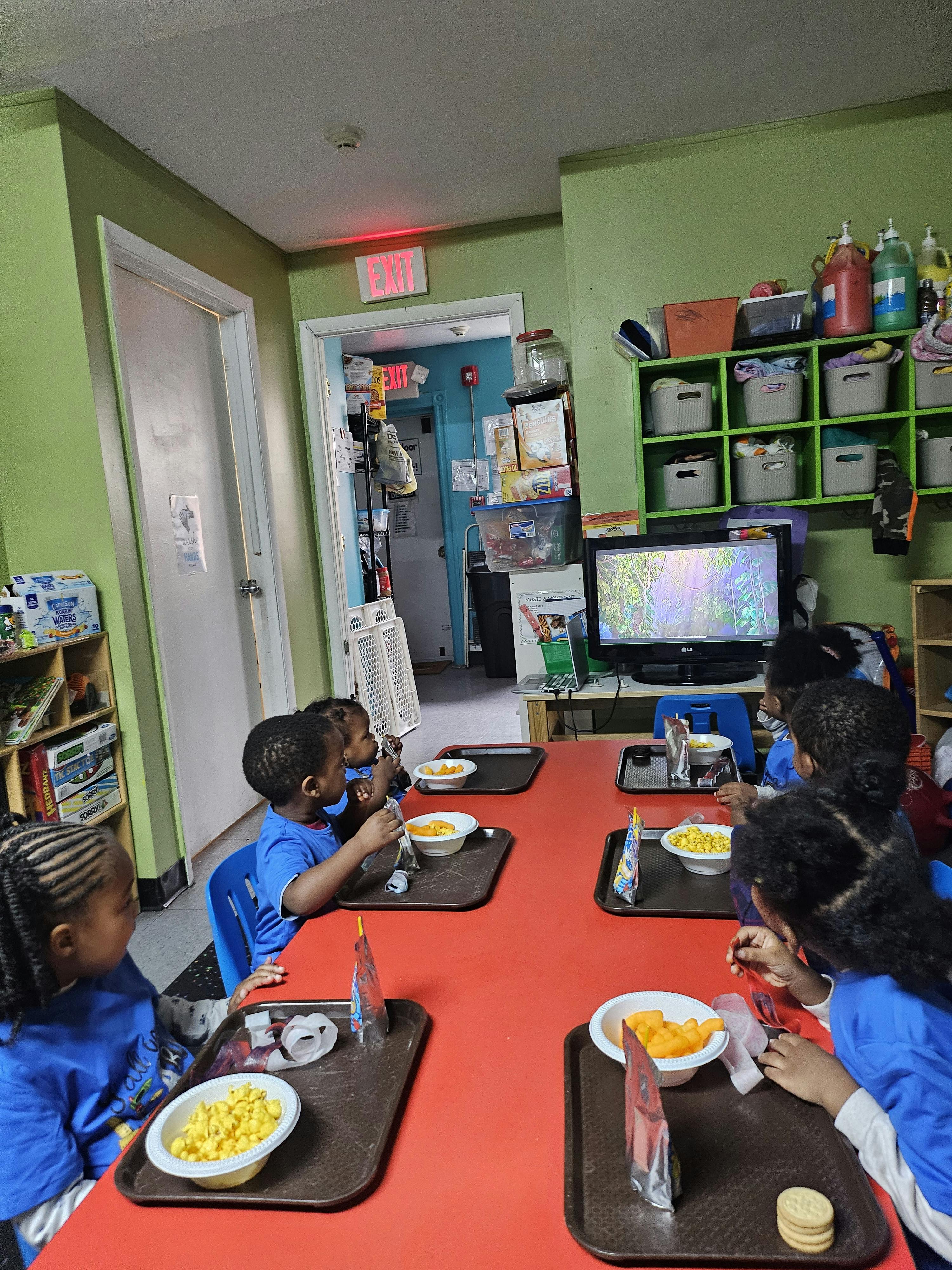 Children eating snacks at a red table in a classroom