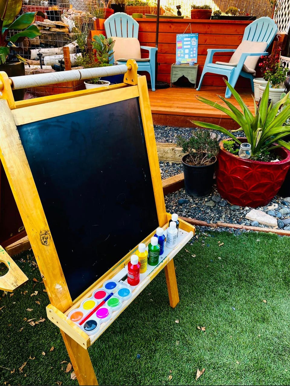 Easel with paints and brushes on grass