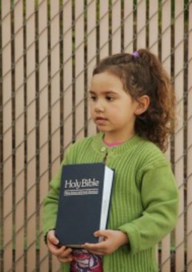 Child holding a book titled "Holy Bible"