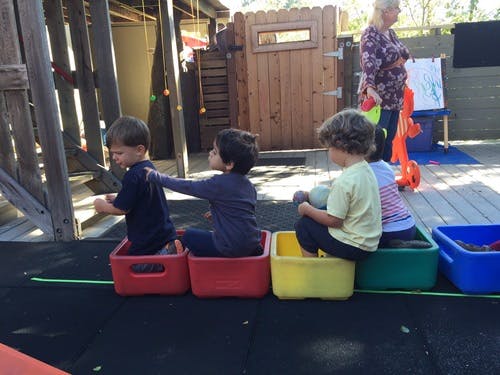 Children sitting in colorful bins in a line