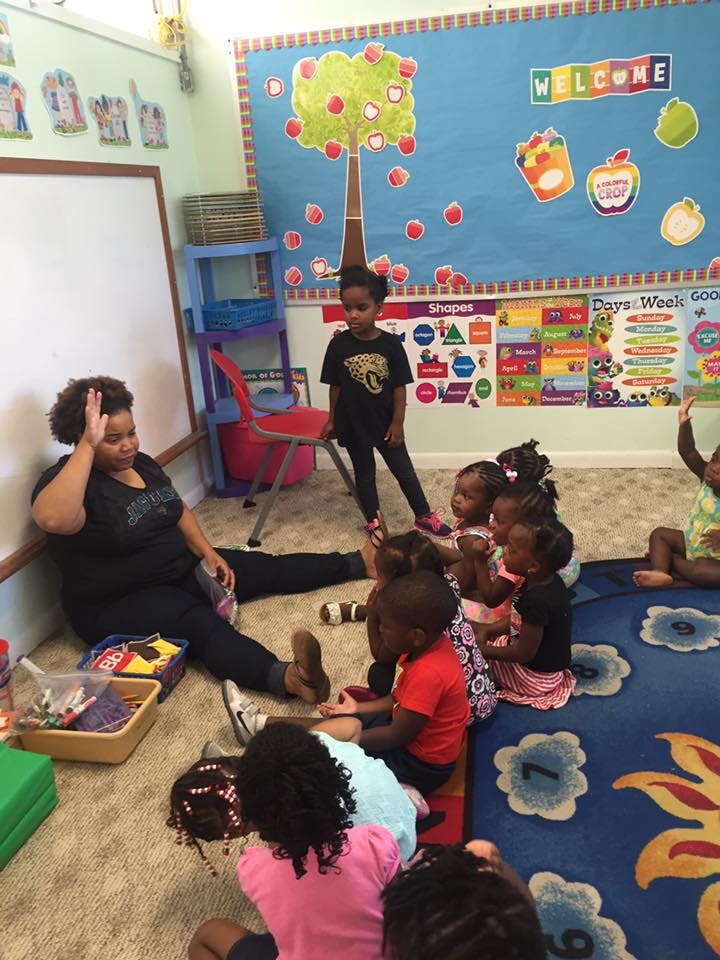 Person sitting on floor with children in a classroom