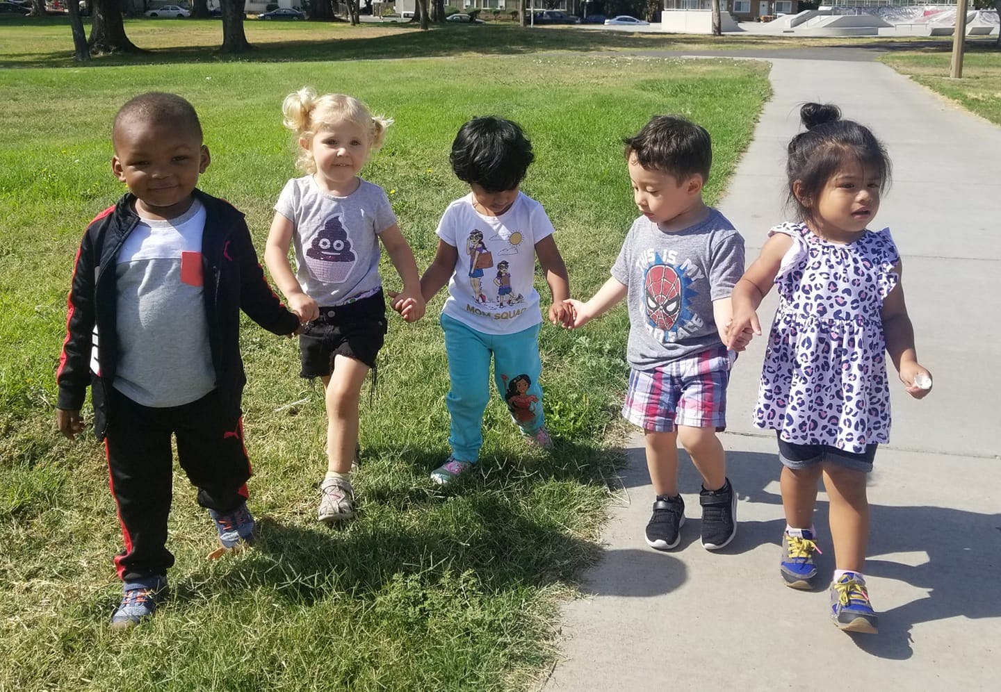 Five children holding hands and walking outdoors