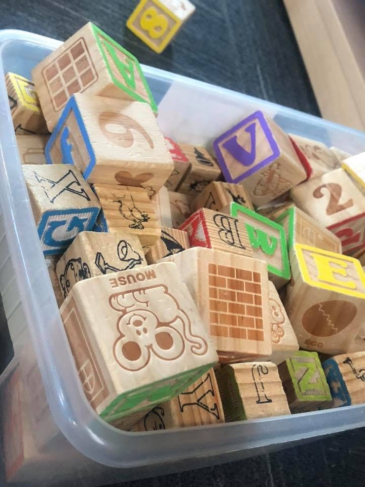 Wooden alphabet and number blocks in a clear plastic bin