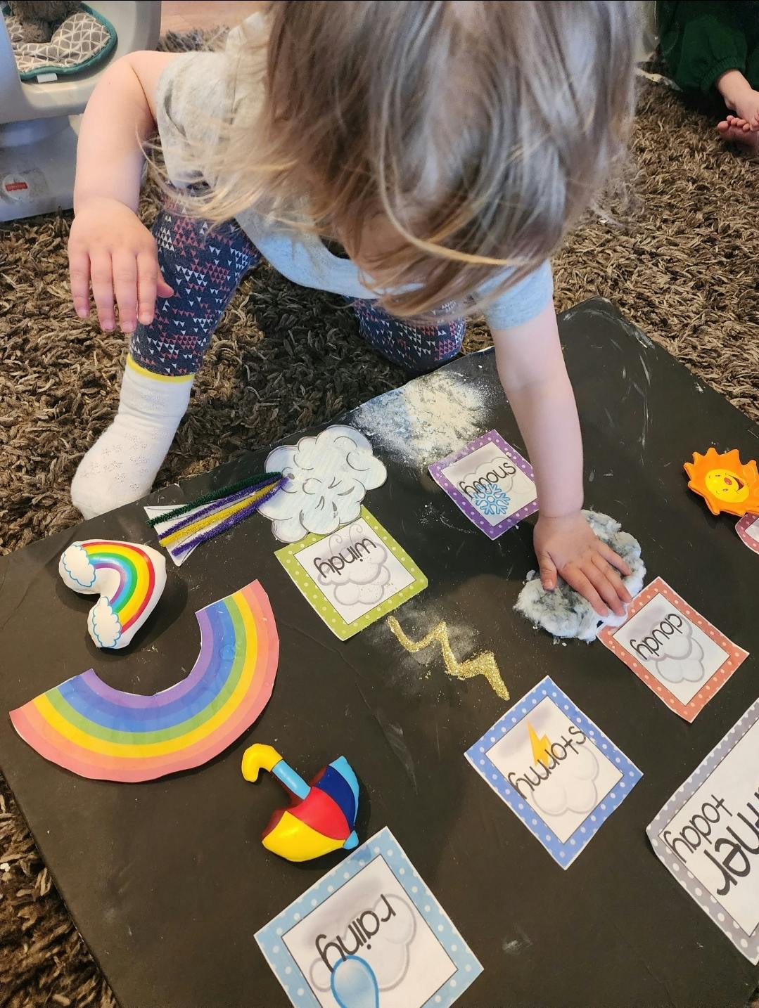 Child playing with weather-themed cutouts and cotton balls of cotton balls