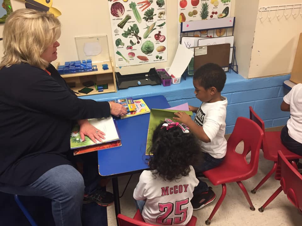 Person and two children at a table with books