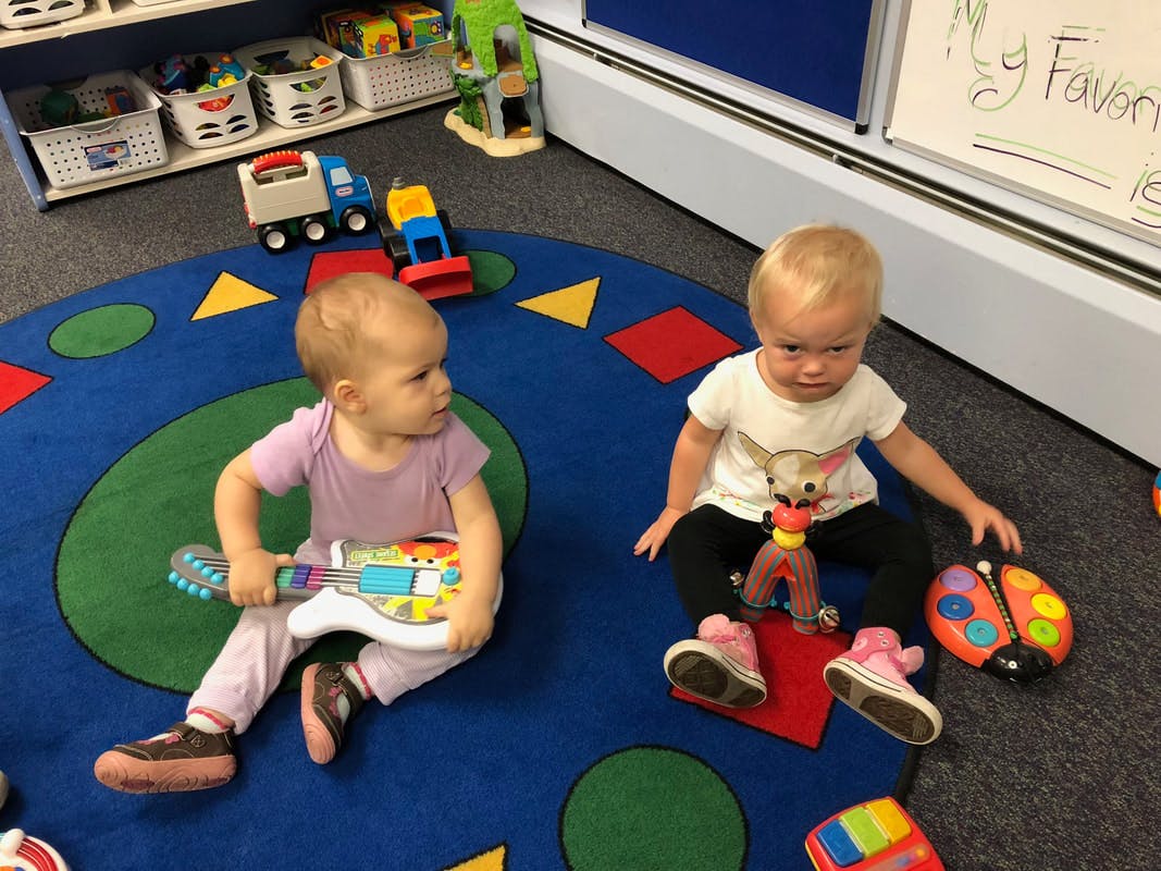 Two children playing with toys on a rug