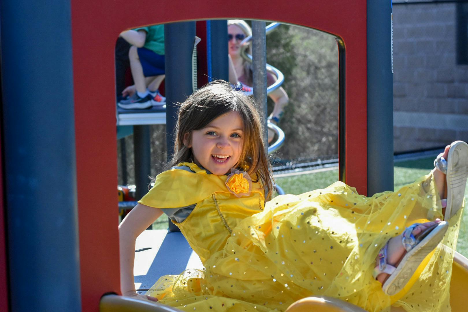 Child in yellow dress on a playground slide