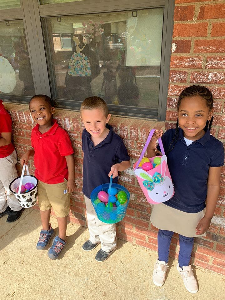 Three children holding baskets filled with colorful eggs