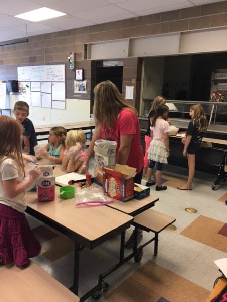Adult and children gathered around tables in a cafeteria