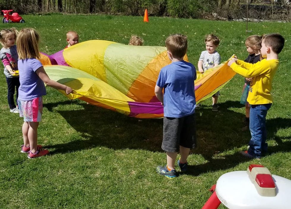 Children playing with a colorful parachute on grass