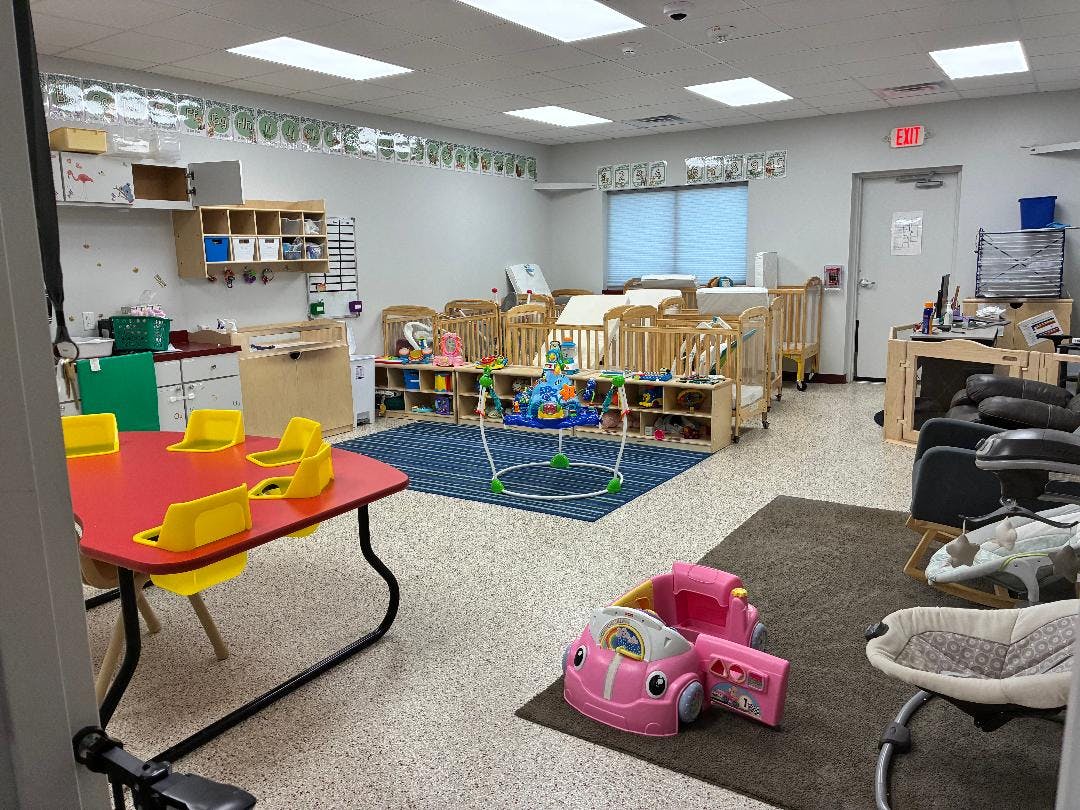 Daycare room with cribs, play mats, and small tables