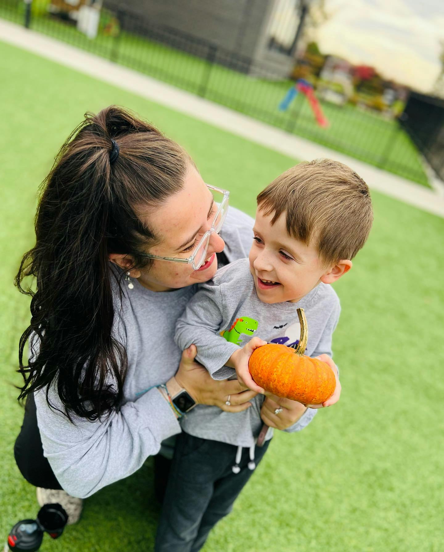 Person holding a child who is holding a small pumpkin