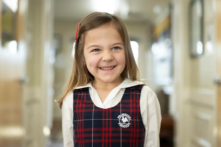 Child in a plaid uniform smiling