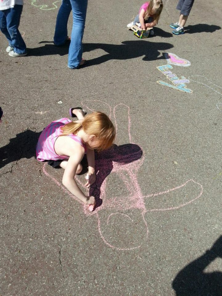 Child drawing with chalk on pavement