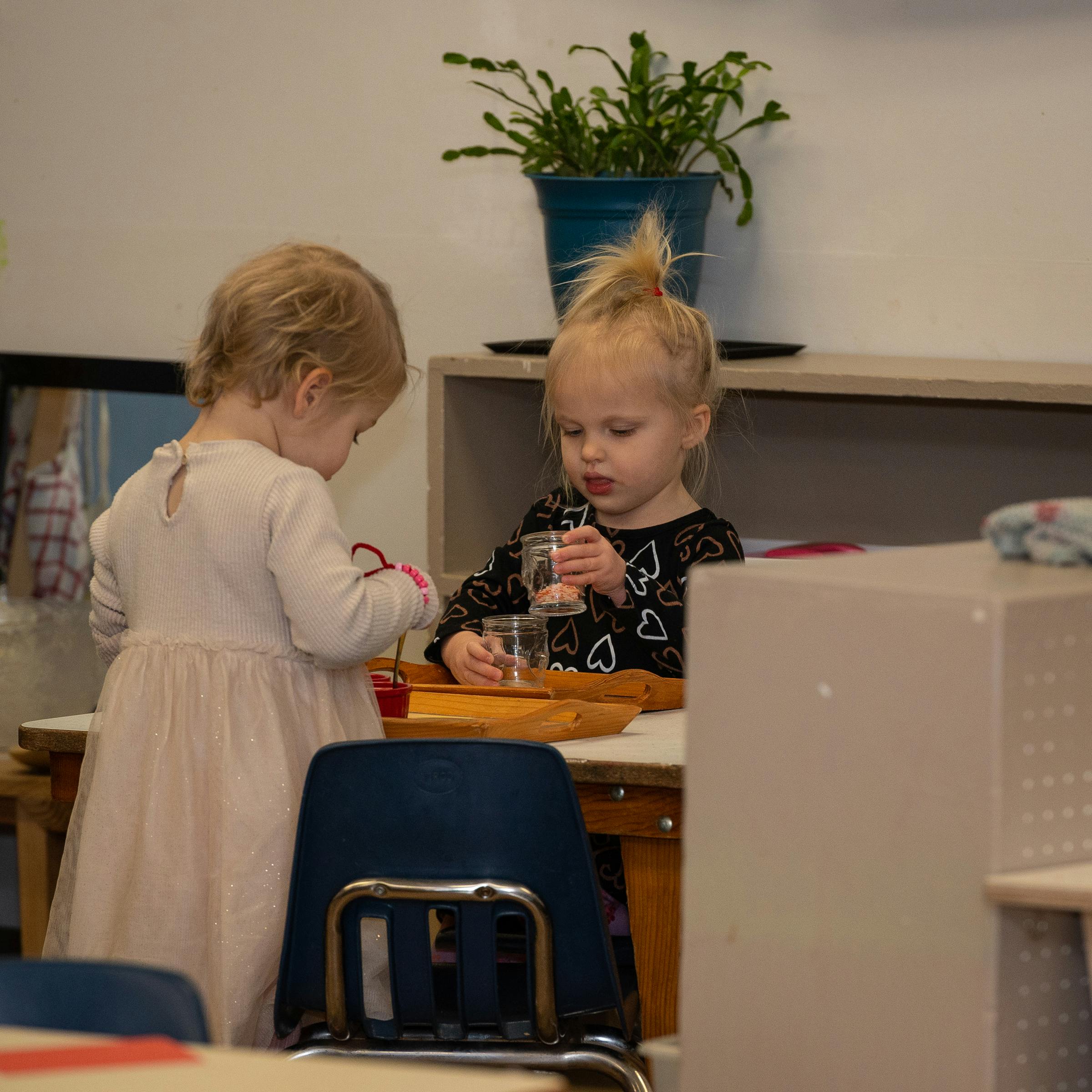 Two children playing with small glasses at a table