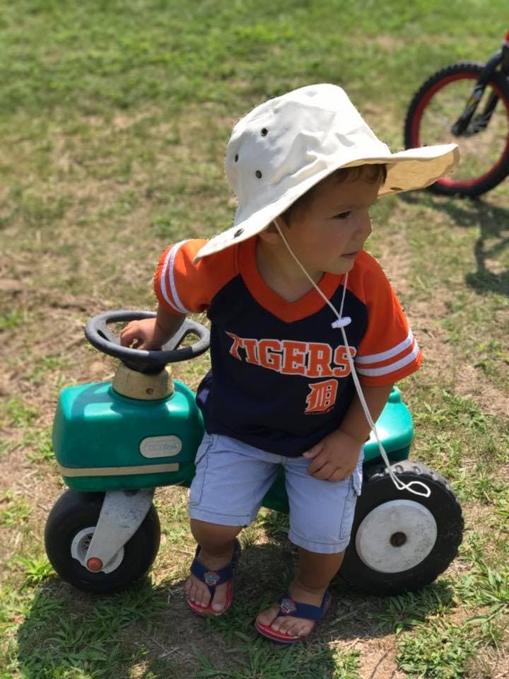 Child in a sun hat sitting on a toy tractor