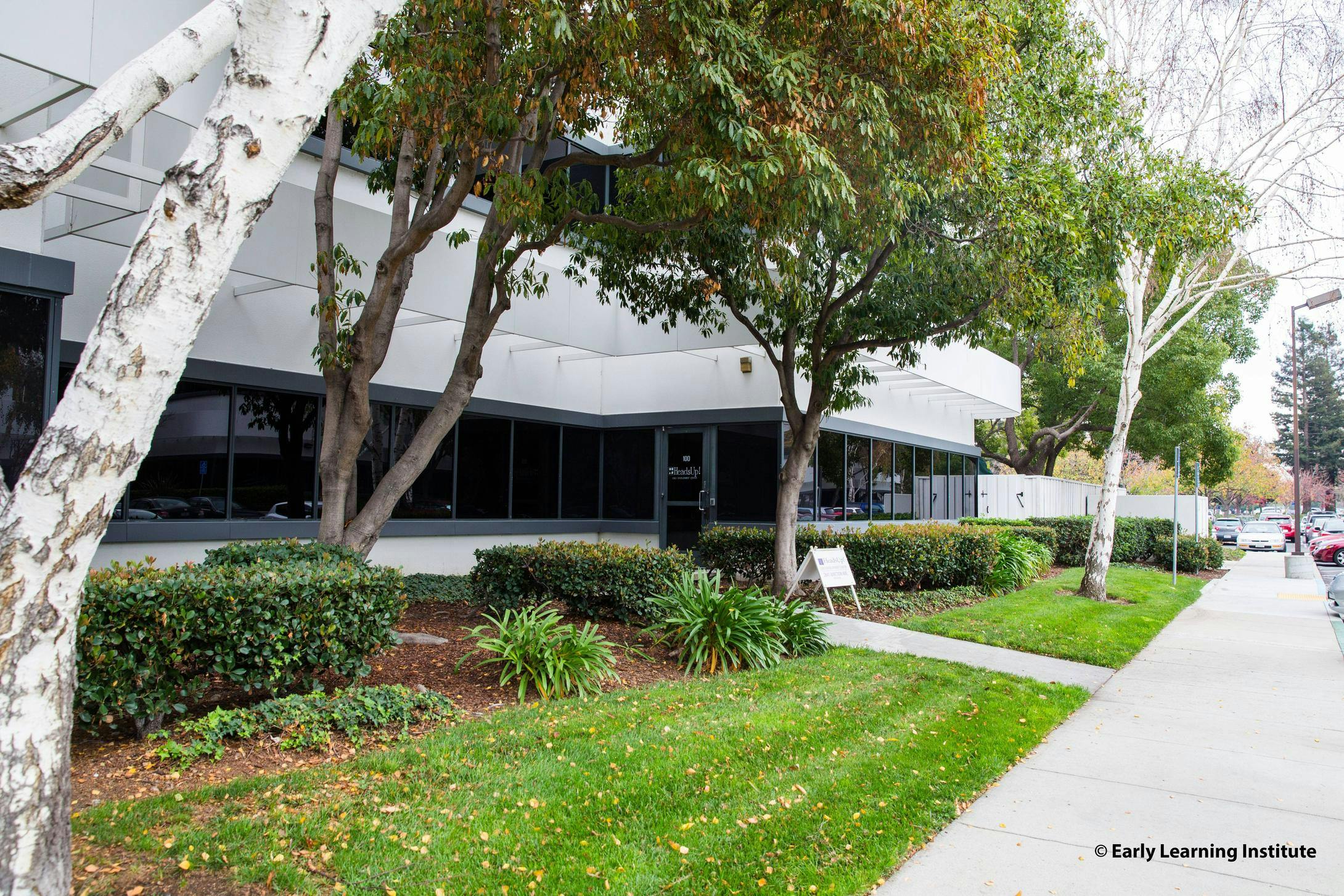 Exterior of a building with trees, bushes, and a sidewalk