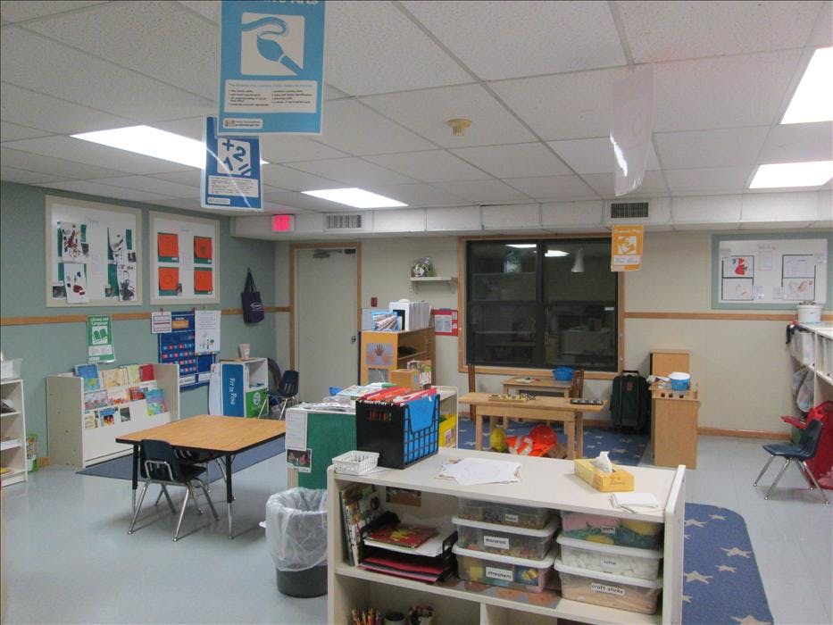 Classroom with tables, chairs, and shelves of materials