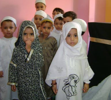 Group of children in traditional clothing, some wearing head coverings