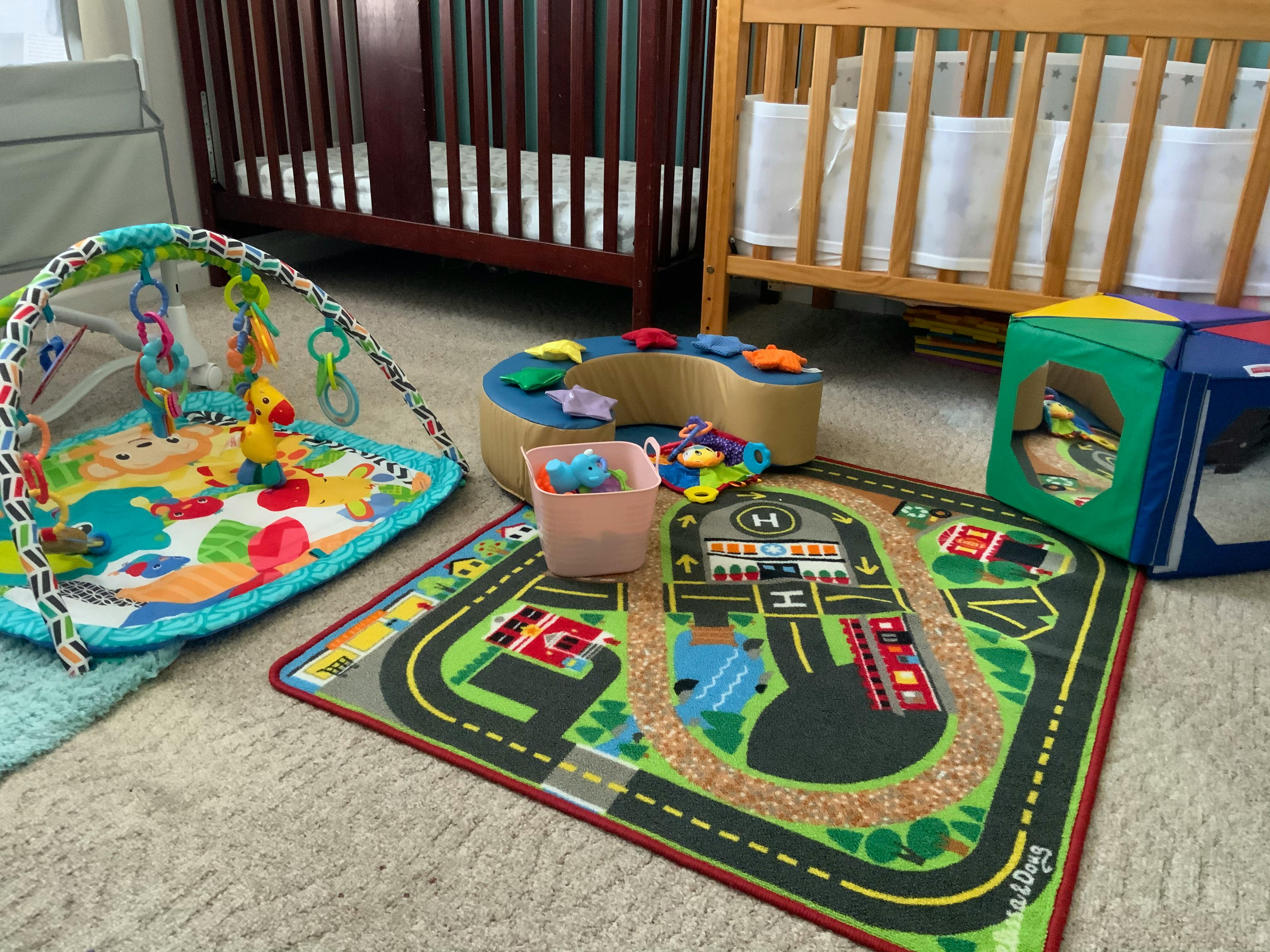 Baby play mat, road rug, and cribs in a room