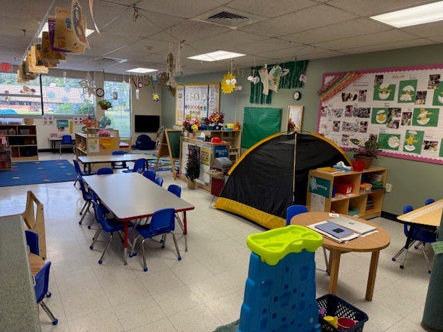 Classroom with tables, chairs, decorations, and a small tent