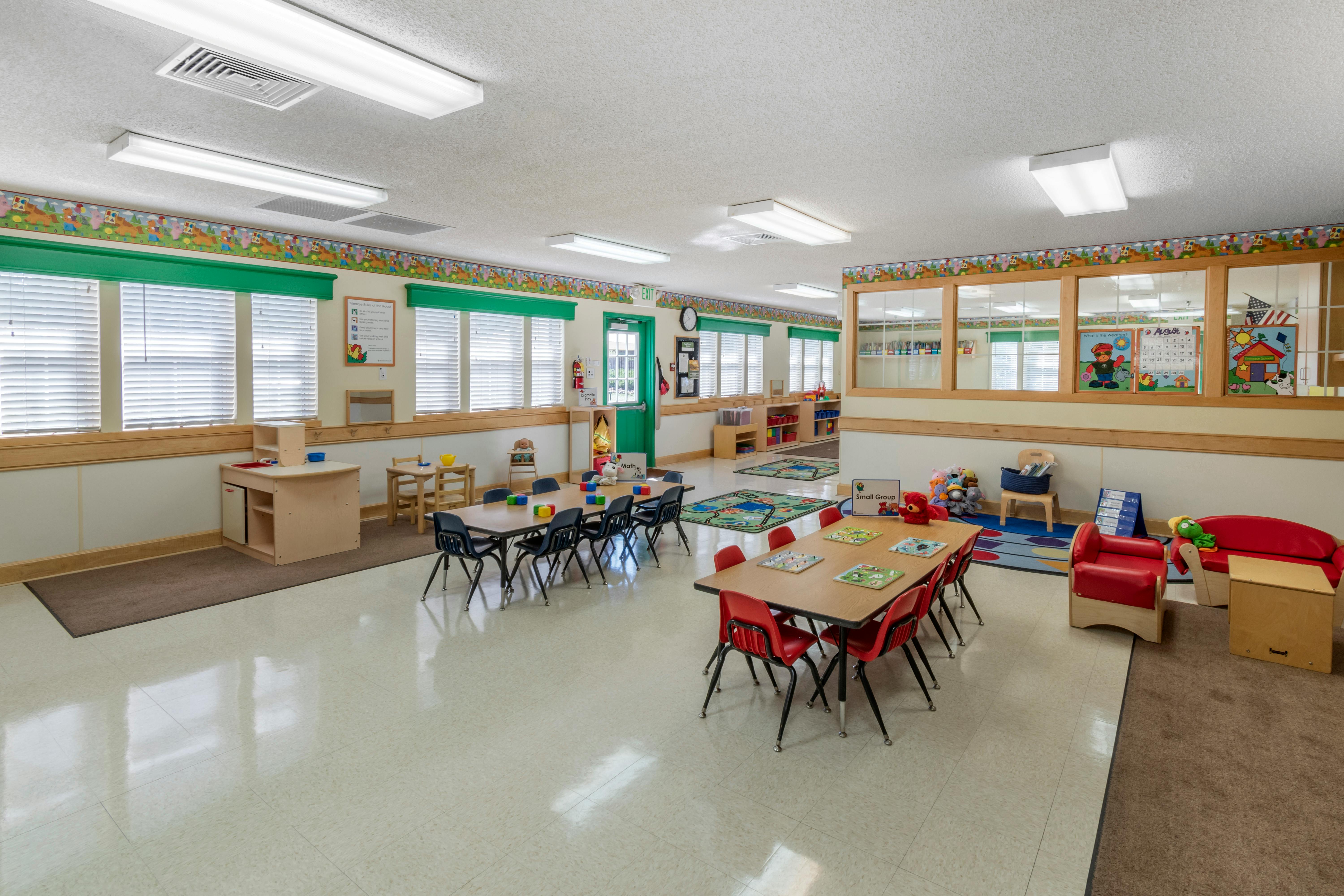 An empty bright preschool classroom with tables and chairs for children