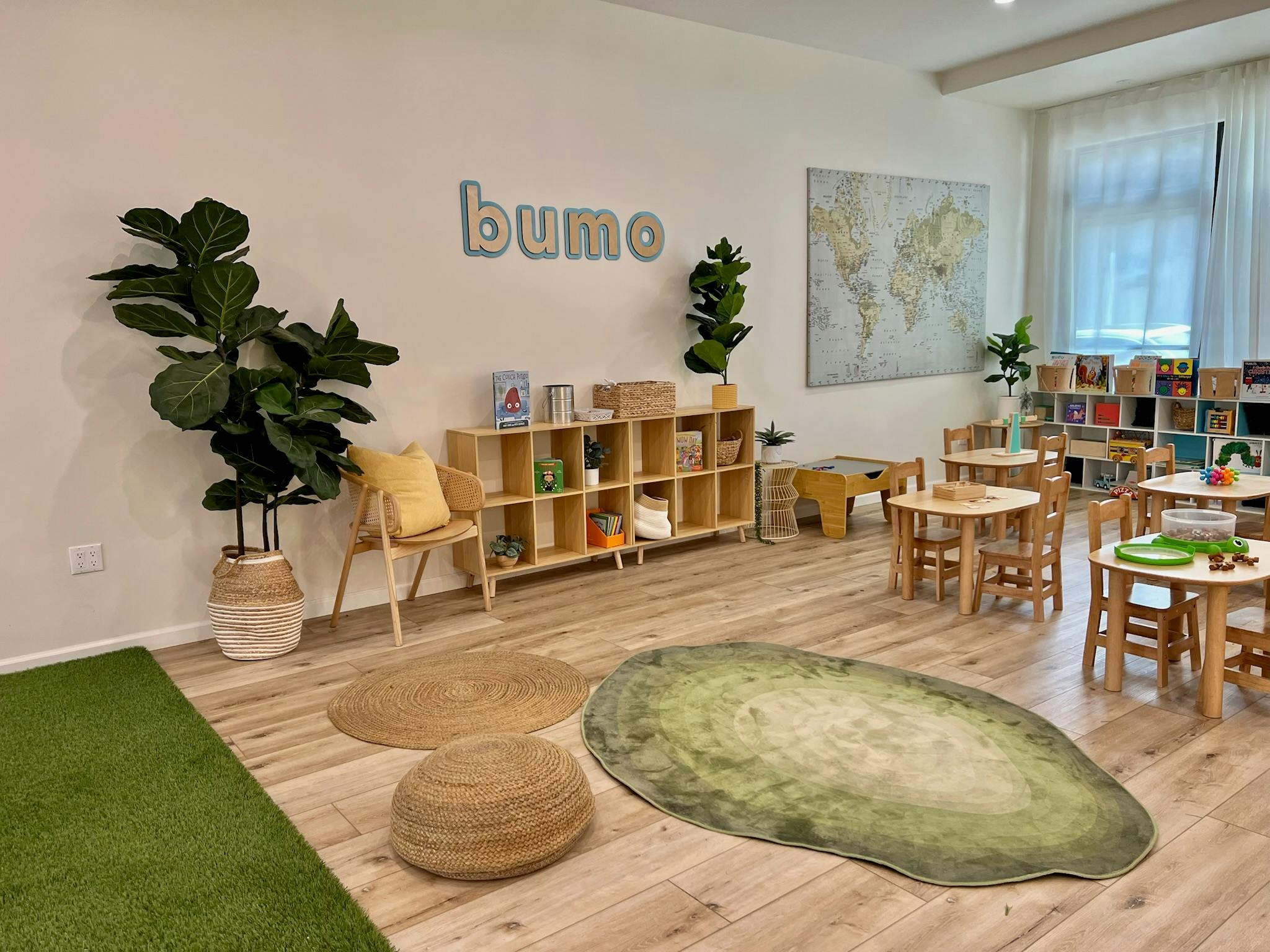 Classroom with small tables and chairs, bookshelves, and a world map on the wall